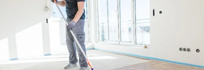 Person trägt Kleber mit Farbrolle auf